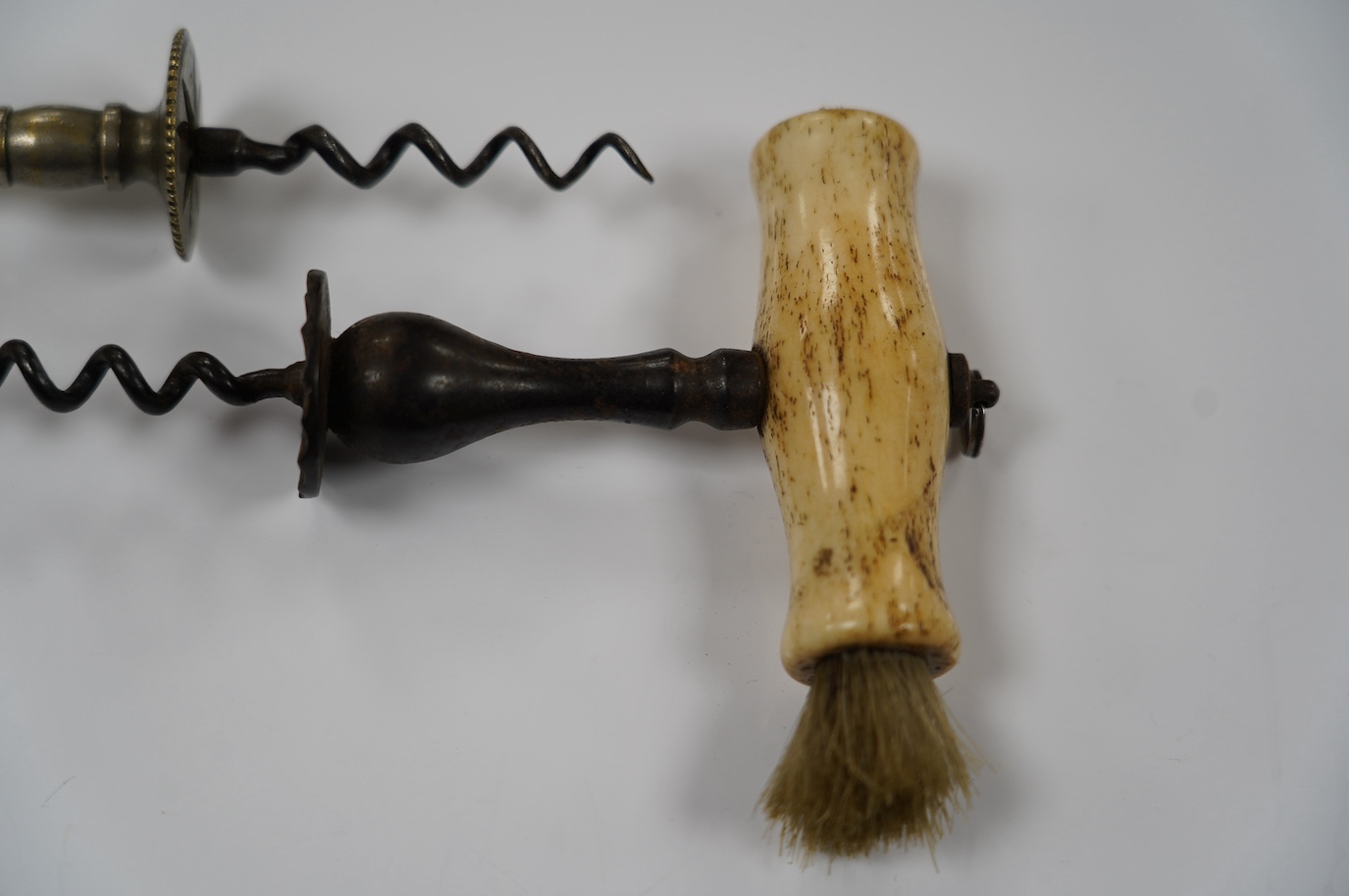 Two early 19th century bone handled corkscrews, one in steel with brush, the other in brass. Condition - good, brass example was silvered, small vacant hole to one end of the handle, no loop or ring